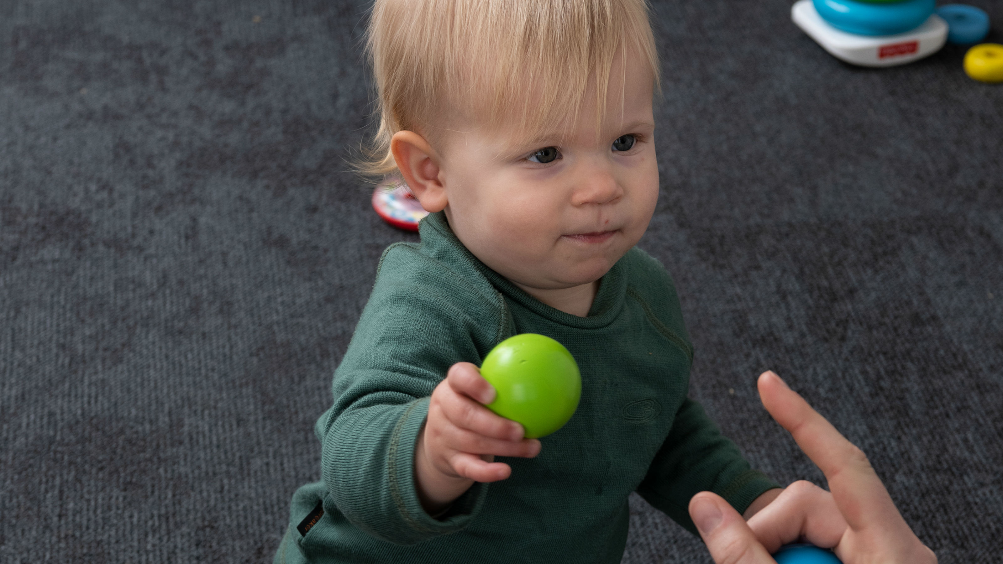 A child passes a green toy ball to an insturctor