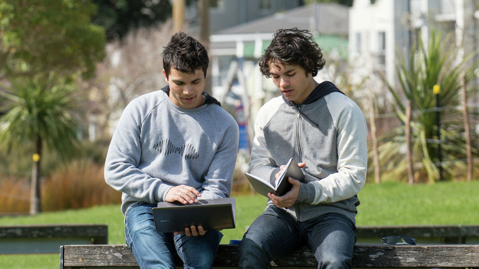 Two students looking at a computer and text book.