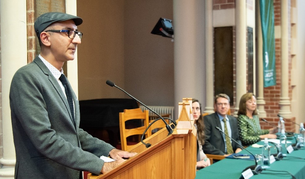 Manjeet speaks at a lectern.