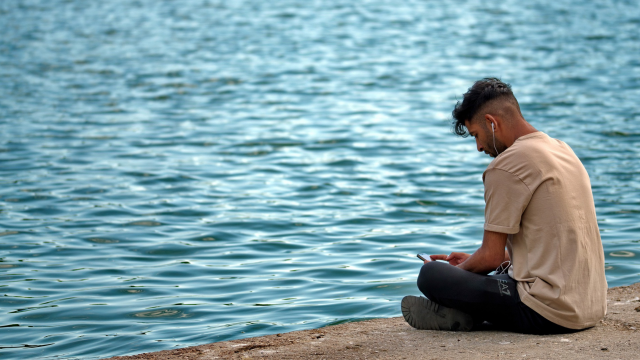 boy listening to headphones on the beach