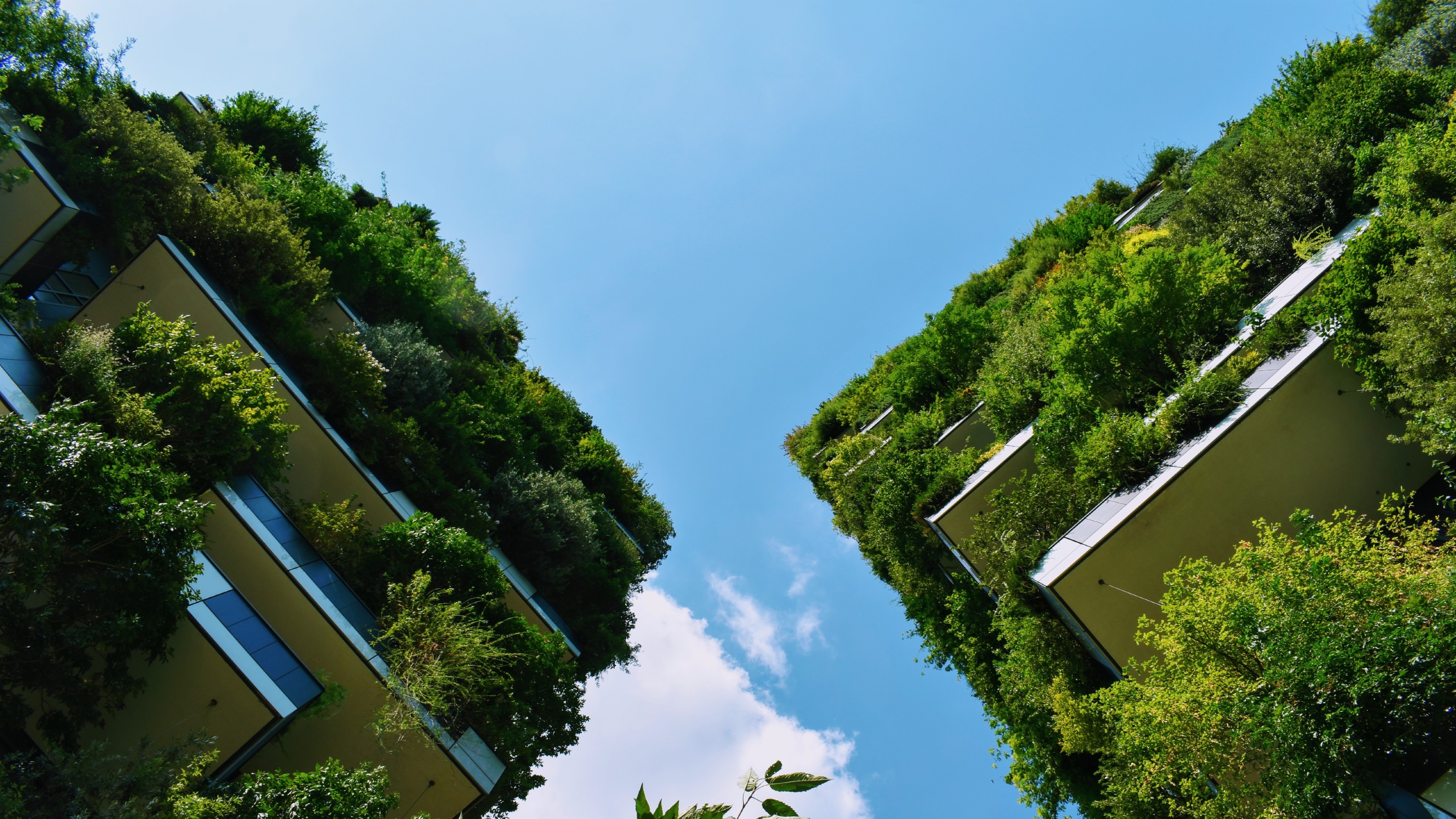 Skyscrapers covered in plants, against a blue sky