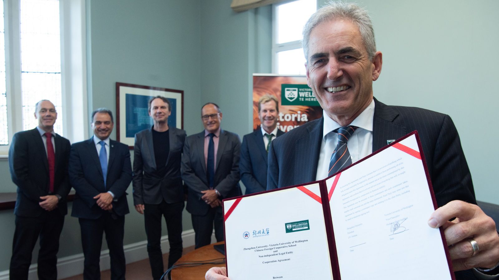 Grant Guilford stands in front of a group, holding a signed agreement
