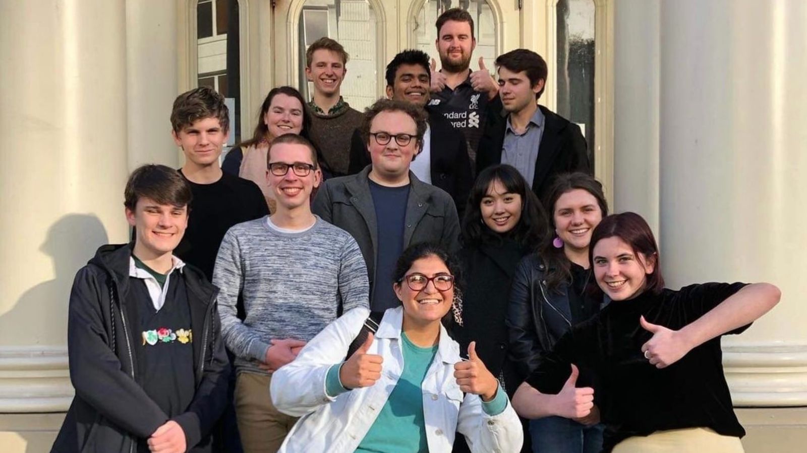 Team picture with members smiling and holding thumbs up.