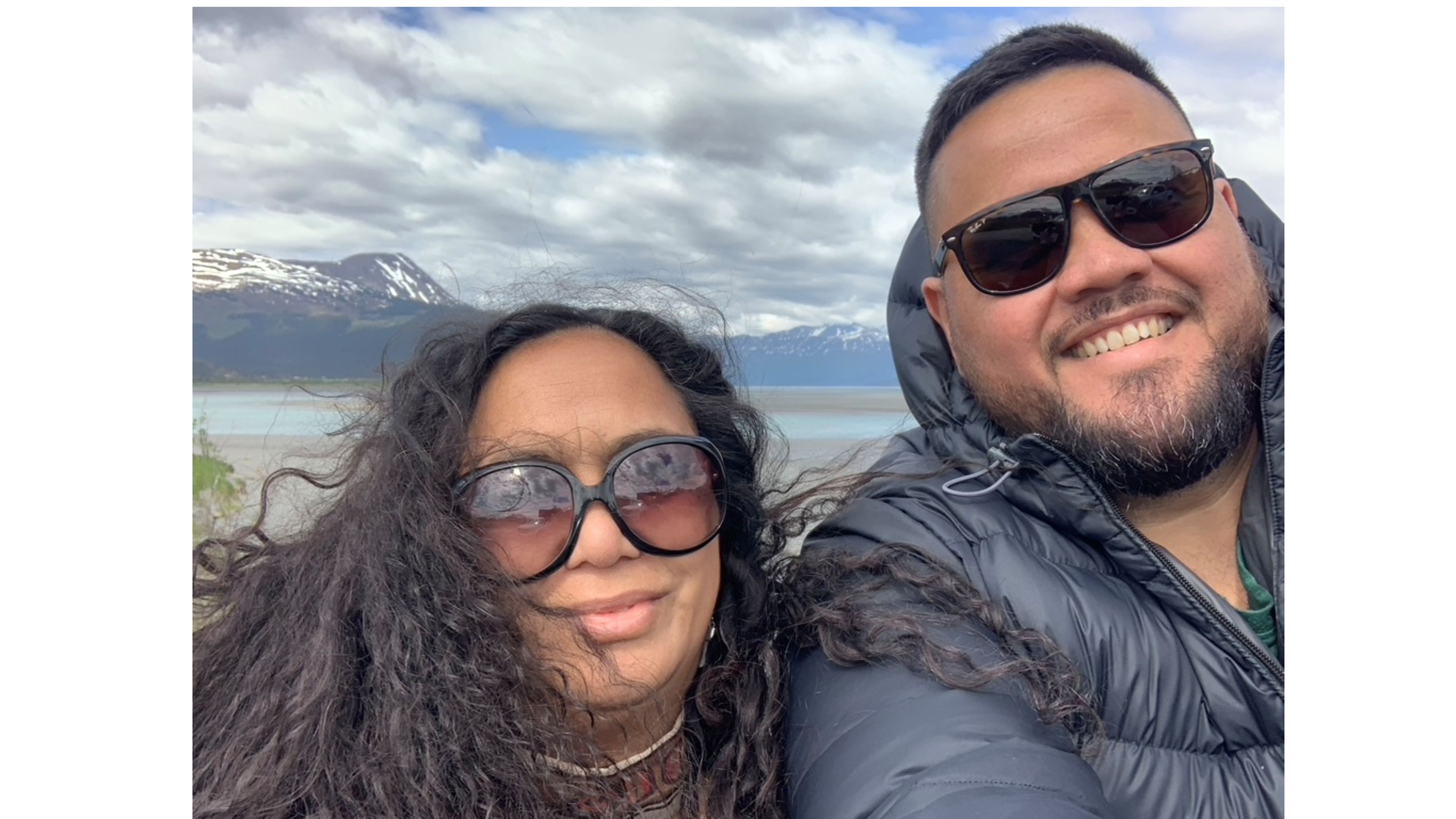 Dr Billy van Uitregt and Cecelia Kumeroa pose in Alaska with snowy mountains and an estuary in the background.