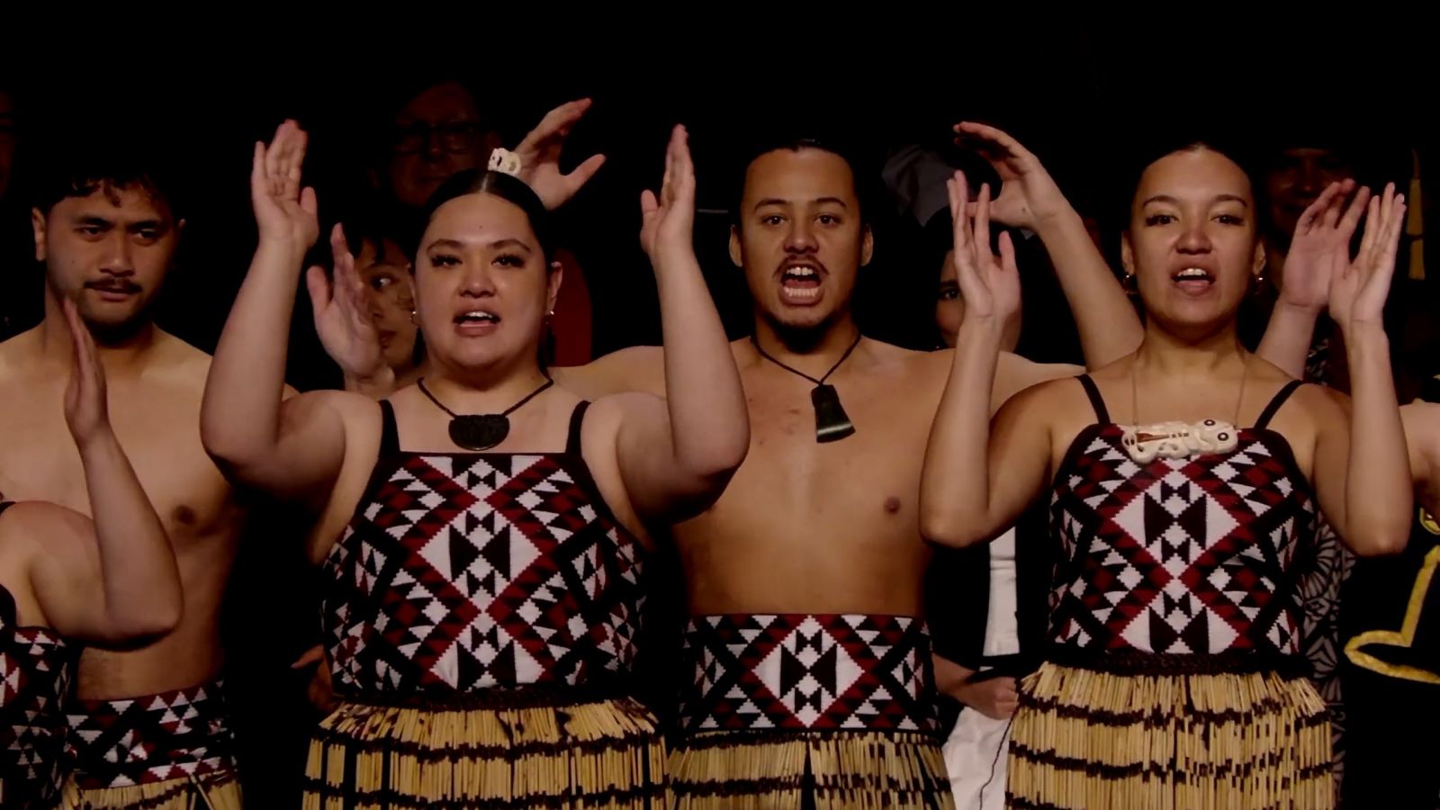 Group performing a haka with raised hands during a graduation ceremony.