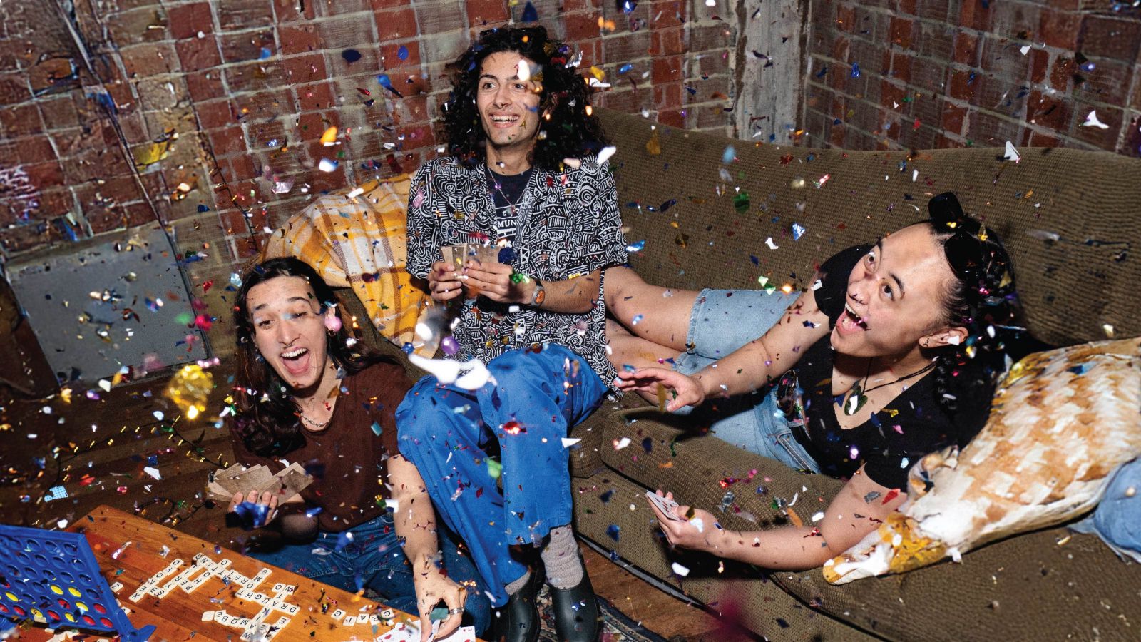 Three students hanging out in the back room of the theatre with confetti going off