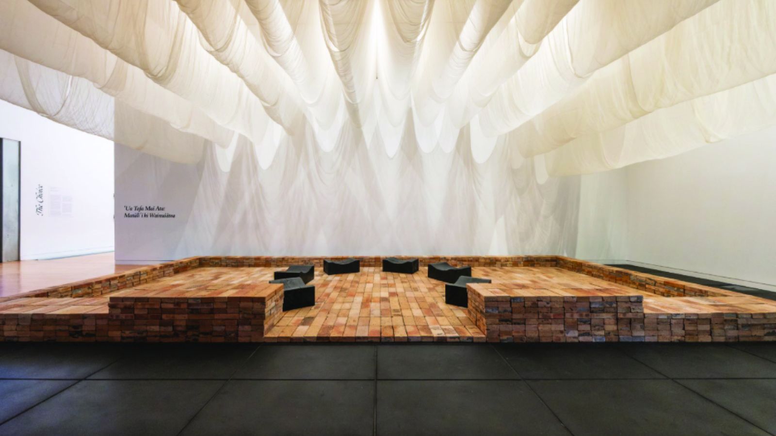Elisabeth Hinemoa Heta artwork with terracotta bricks, sharkstooth gauze and charred macrocarpa in the Adam Art Gallery