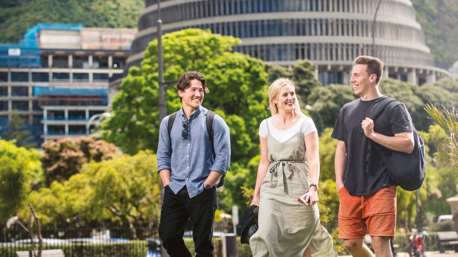 Three students walking past the Beehive, Parliament Buildings, in Wellington.