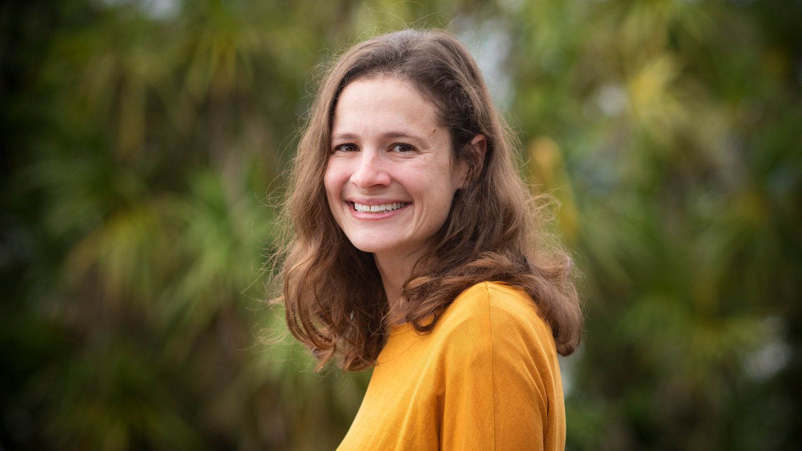 PhD Candidate Laura Kranz posing for a photo in front of green foliage