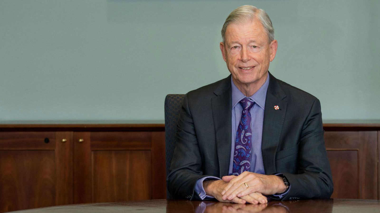 Man in suit with purple tie, with background of dark panelled oak and duck egg blue