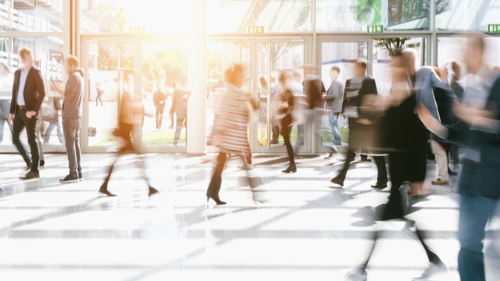 Abstract image of people walking around the foyer of an office building.