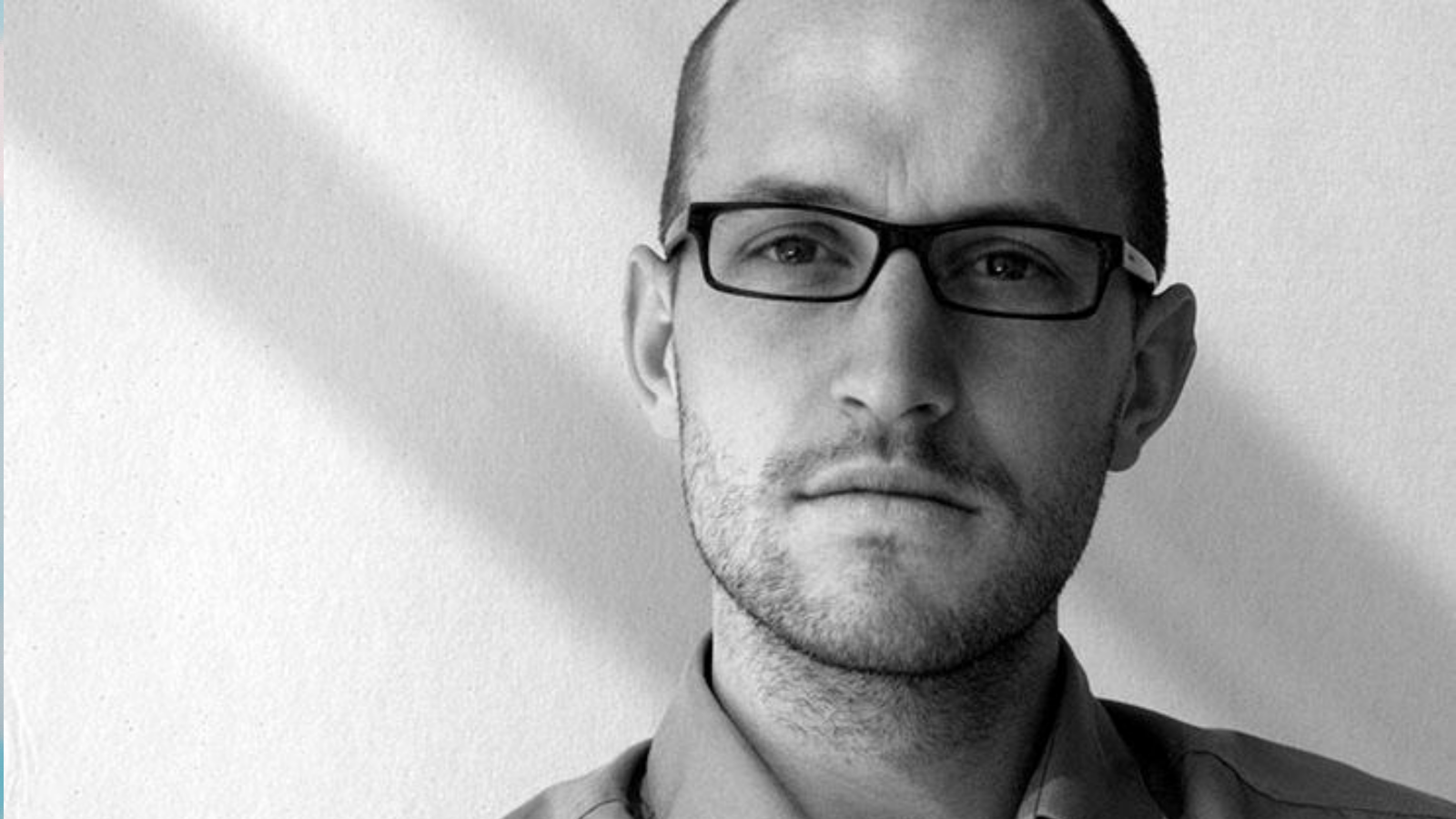 black and white photo of a man with glasses and a black and white blurry background