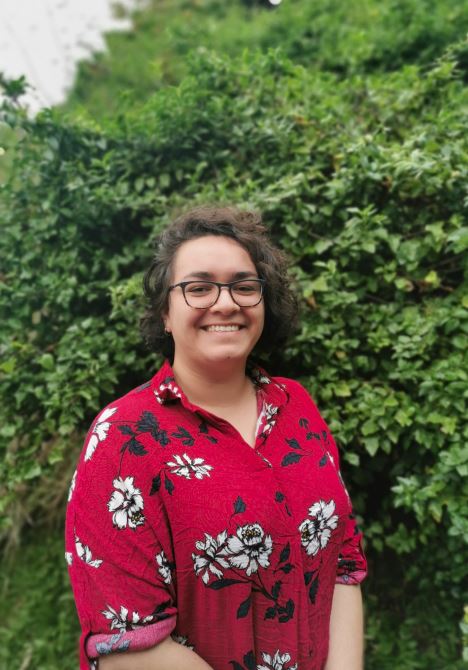 Kaitlin Abbott standing with bush in background.