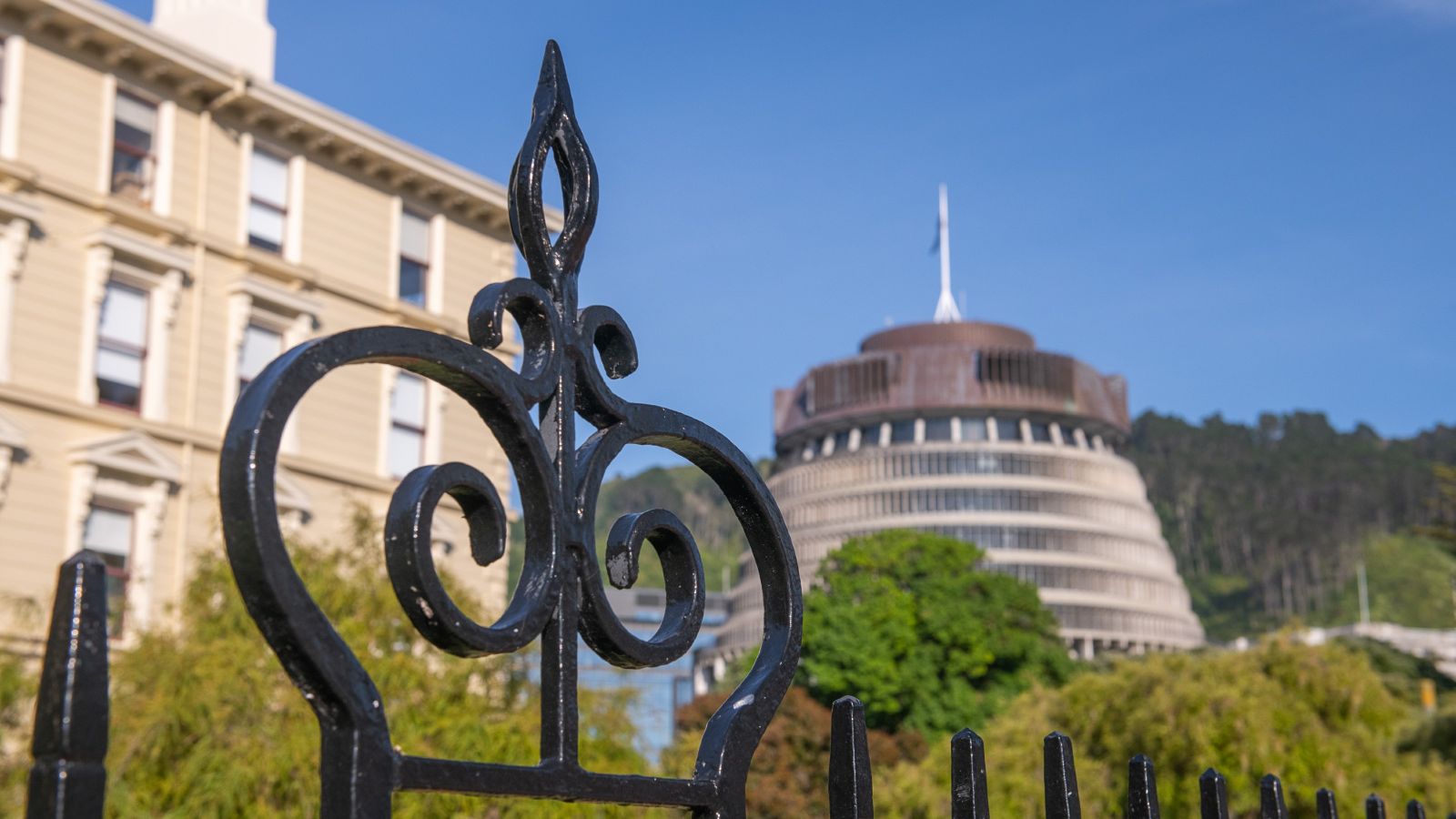 Crown-shaped black gate in foreground with NZ parliament building in background