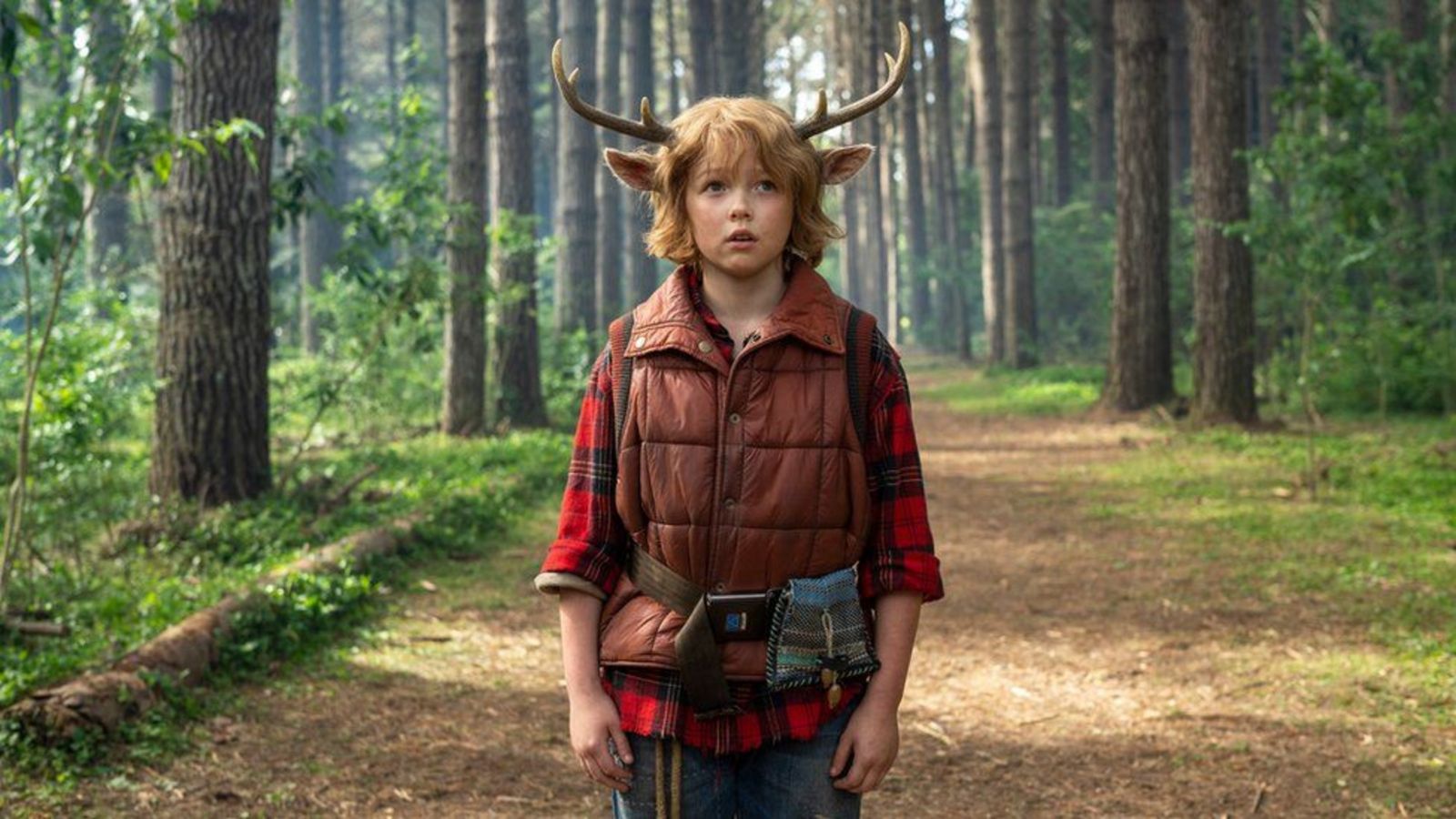 Hybrid human-animal boy with deer horns and ears in woods