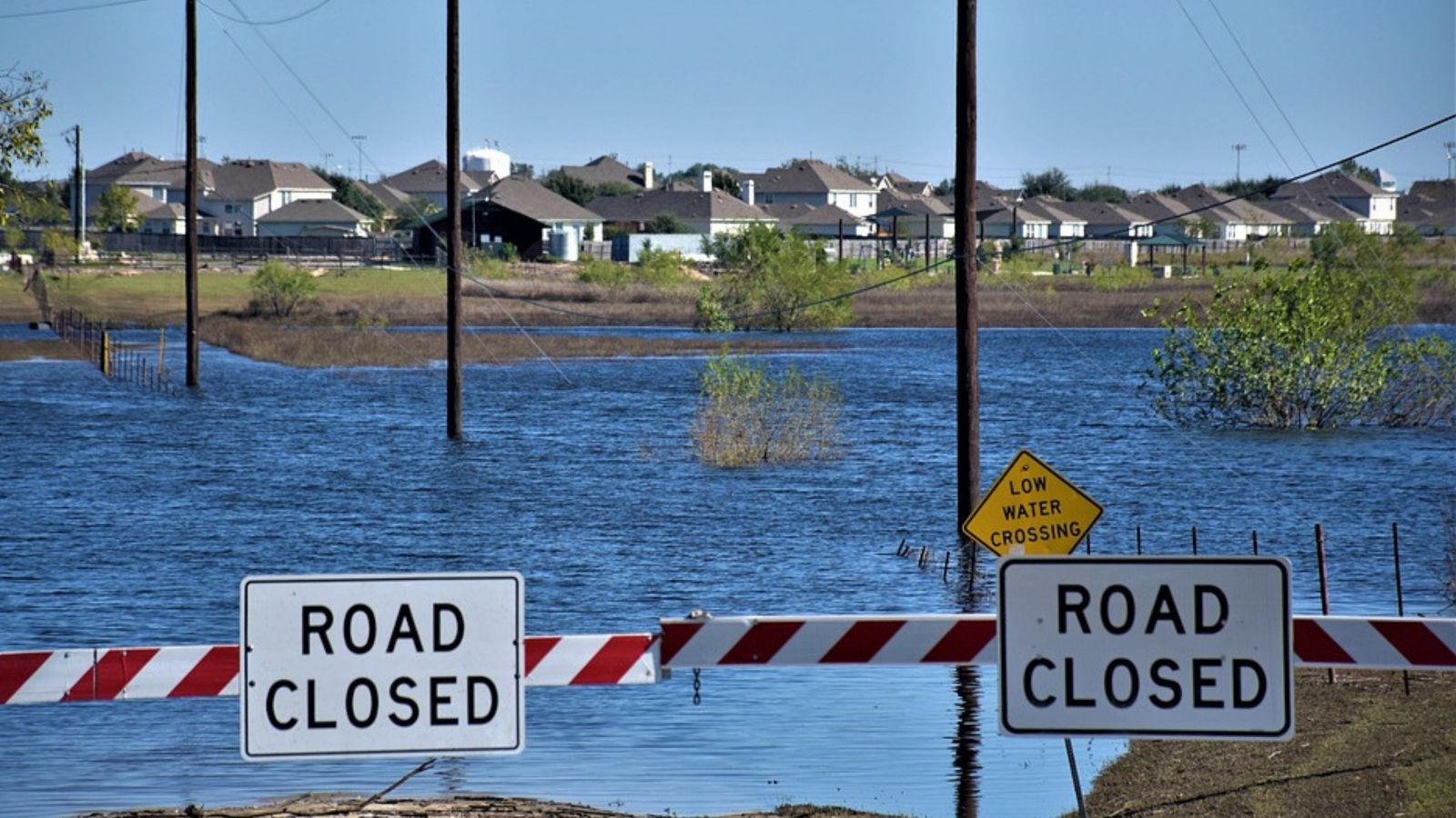 sign with 'road closed' on two sides, with flooded plains behind