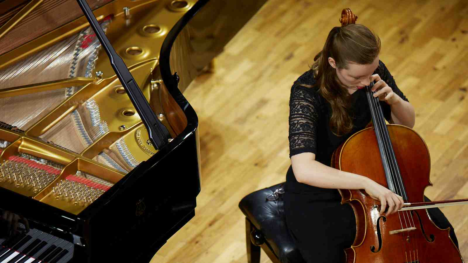Music student plays cello with grand piano accompaniment