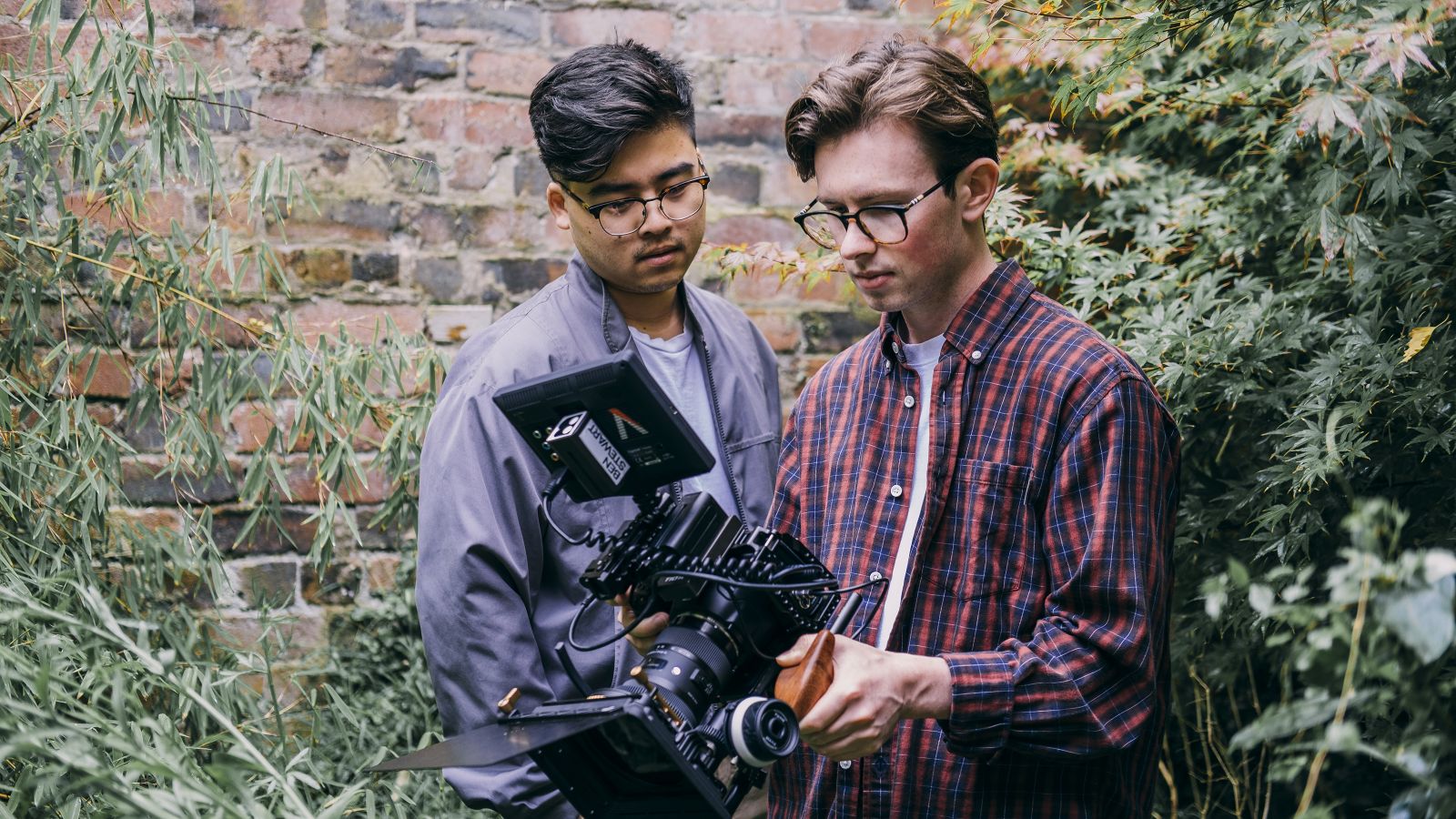 William Cho and Ben Stewart looking at a video camera.
