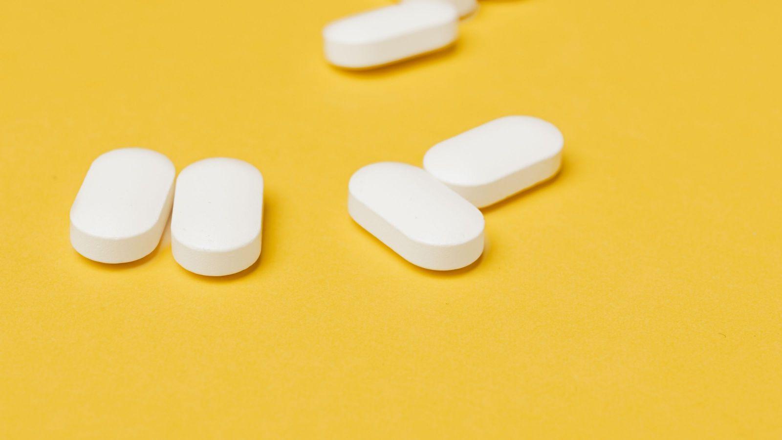 Group of white pills on yellow background