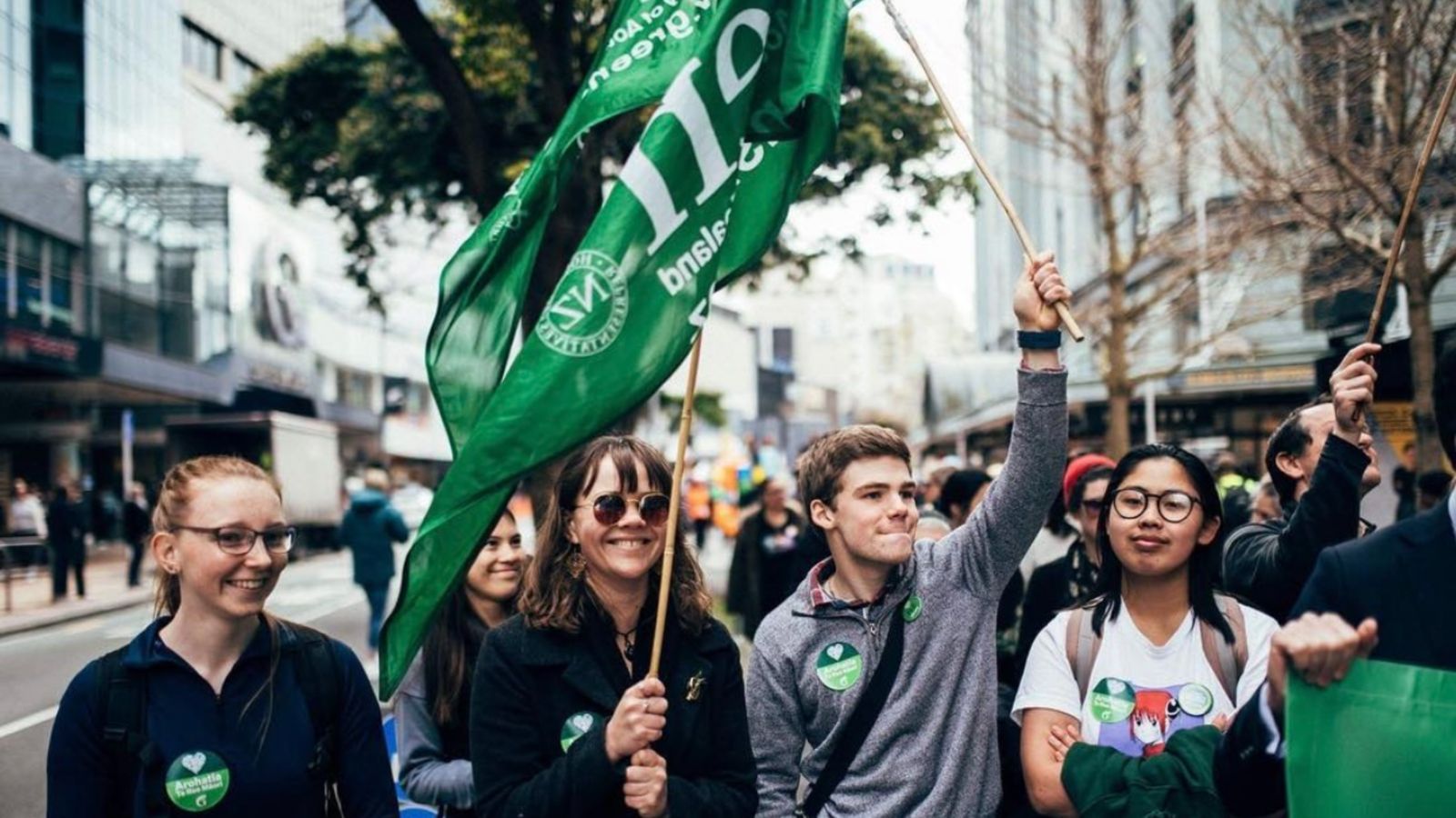 Four students marching with greens flags during protest in Wellington CBS.