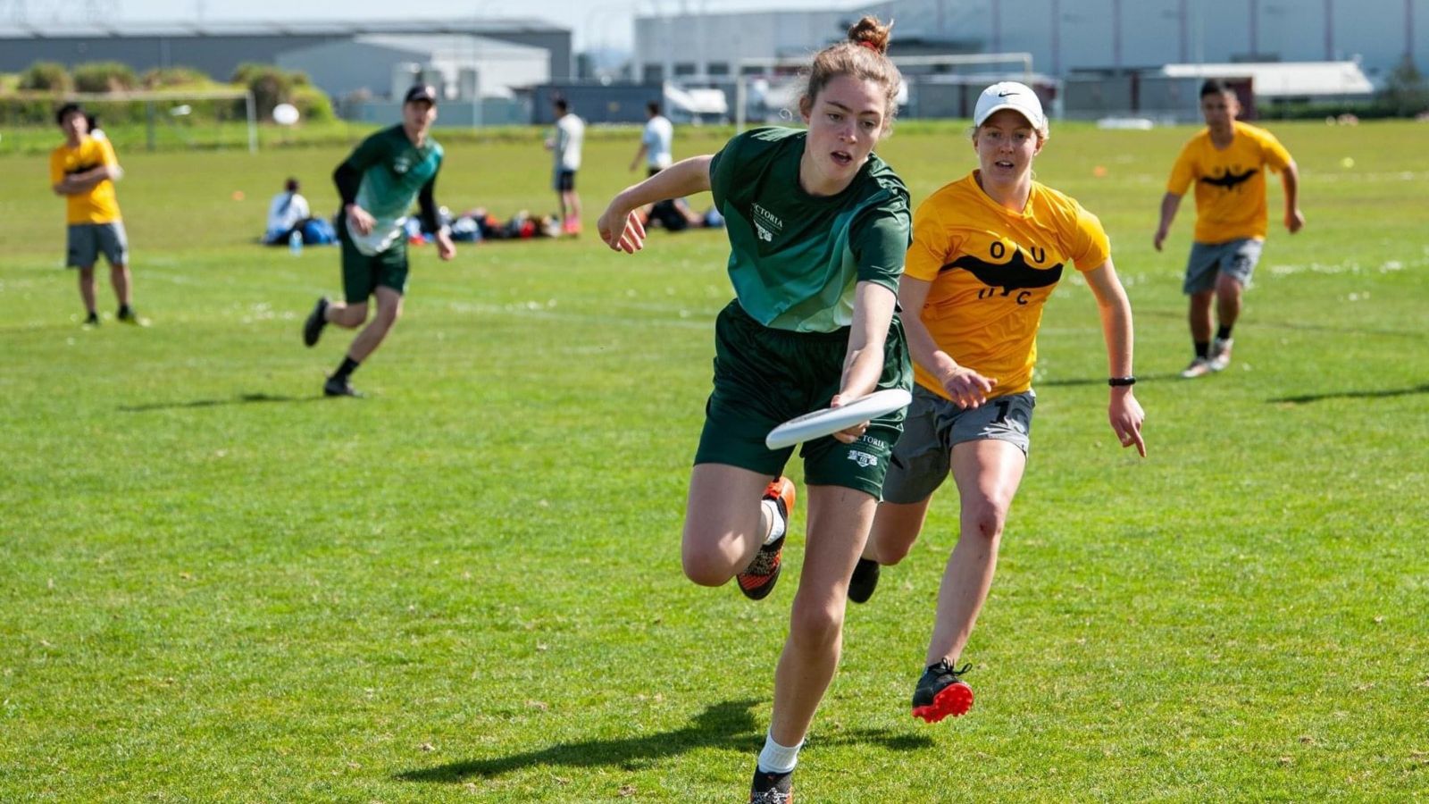 Player catching frisbee while running, with opponents behind.