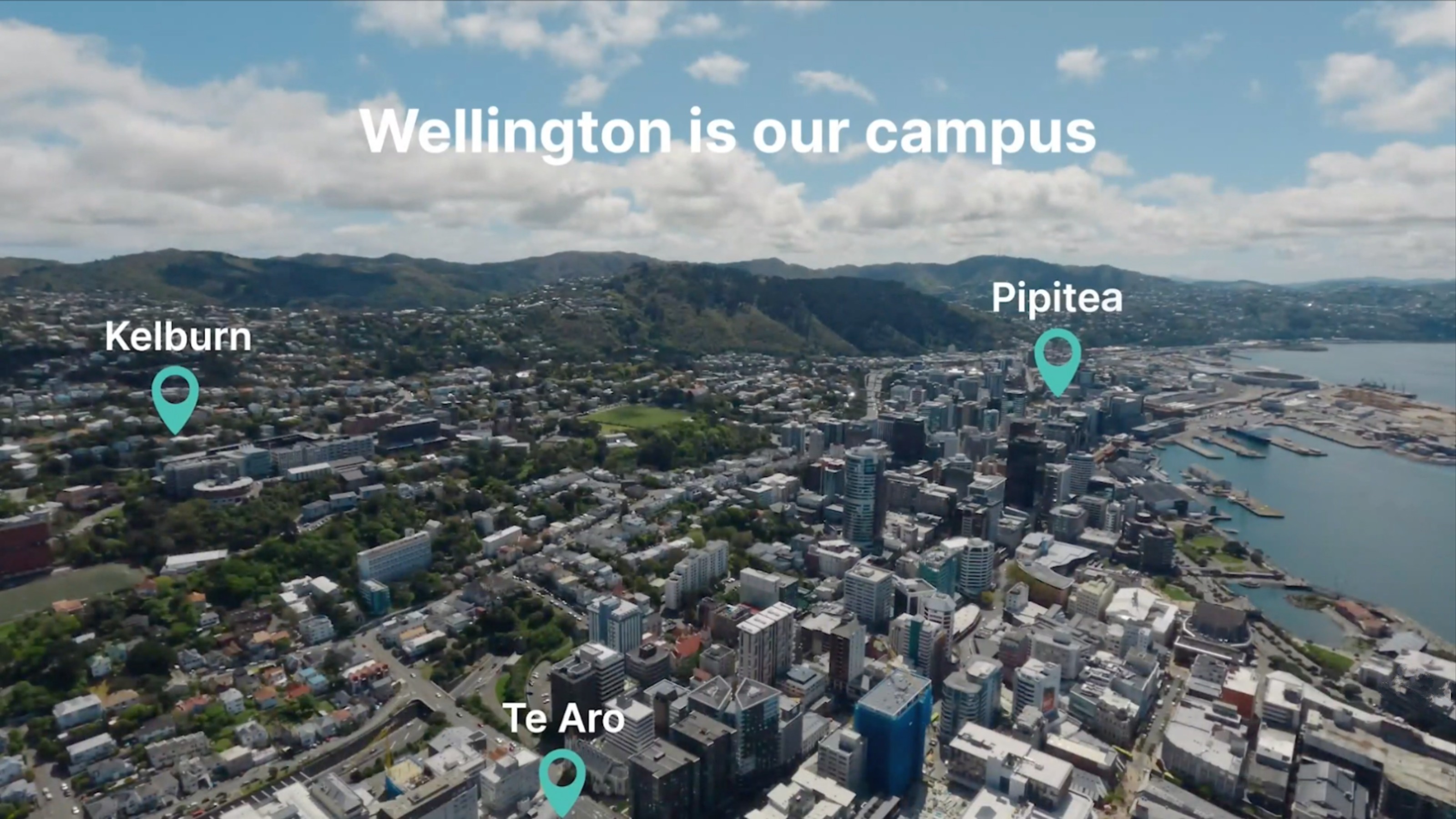 An aerial view of Wellington with green location pins for Kelburn, Pipitea and Te Aro campuses. Across the top of the photograph against a blue sky with clouds, white text reads 'Wellington is our campus'