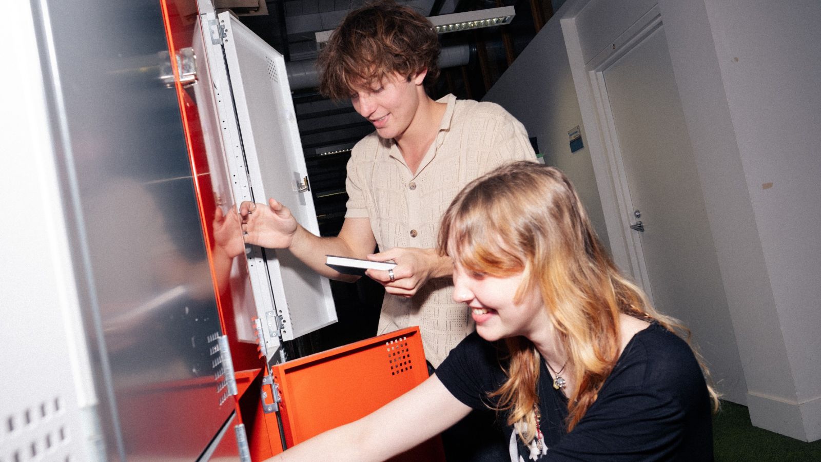 A male and female students put items into their lockers
