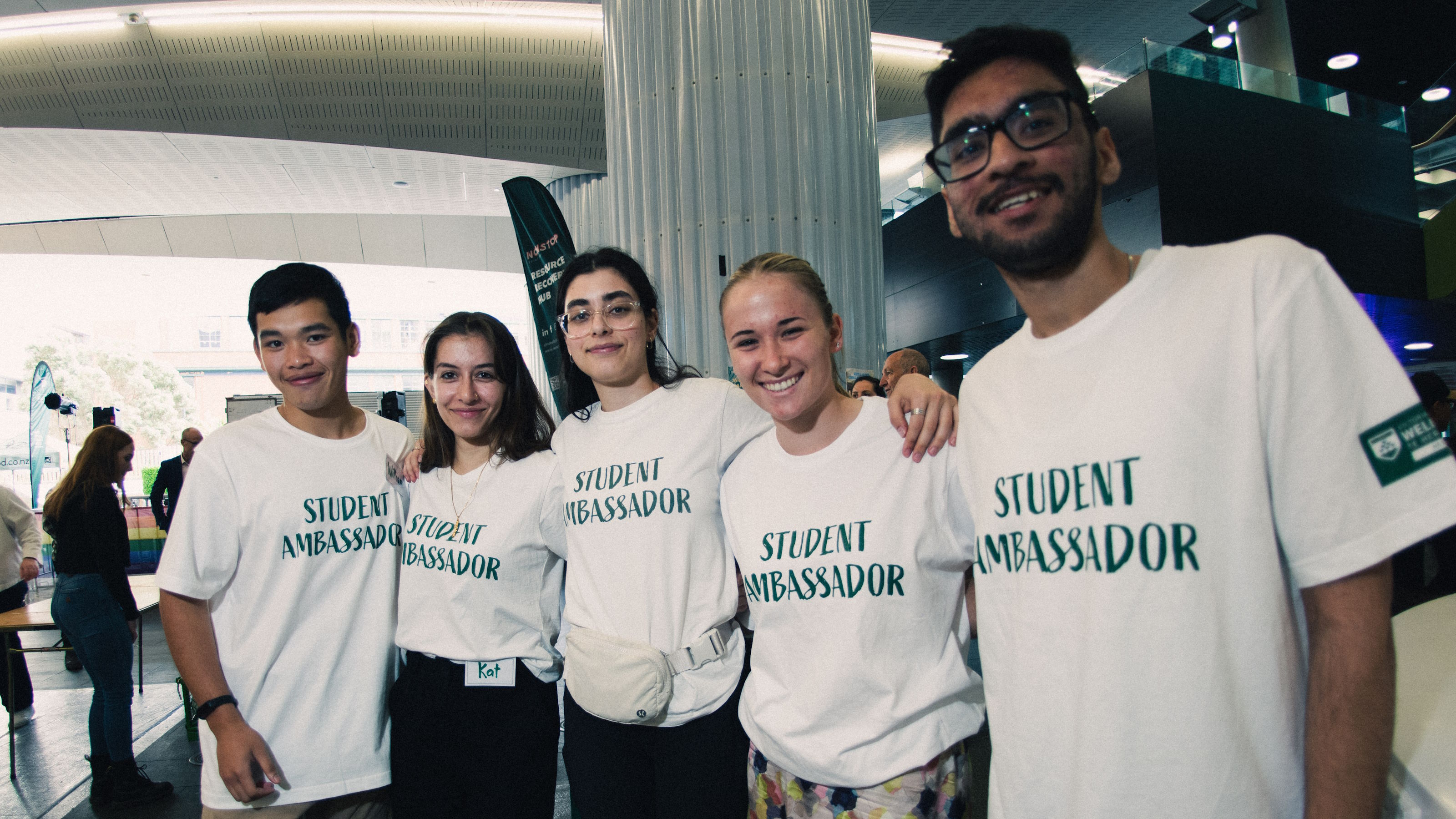 Five smiling students wearing T-shirts saying 