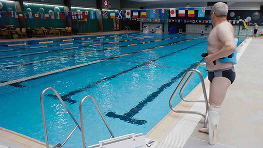 Swimmer standing next to swimming pool wearing the 3D prosthesis.