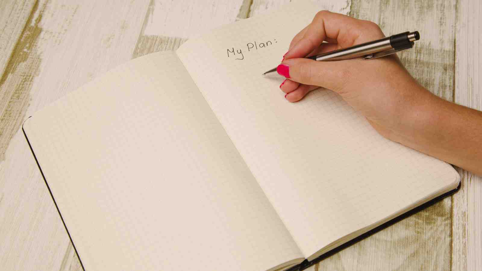 A hand writing 'My Plan' in a blank book.