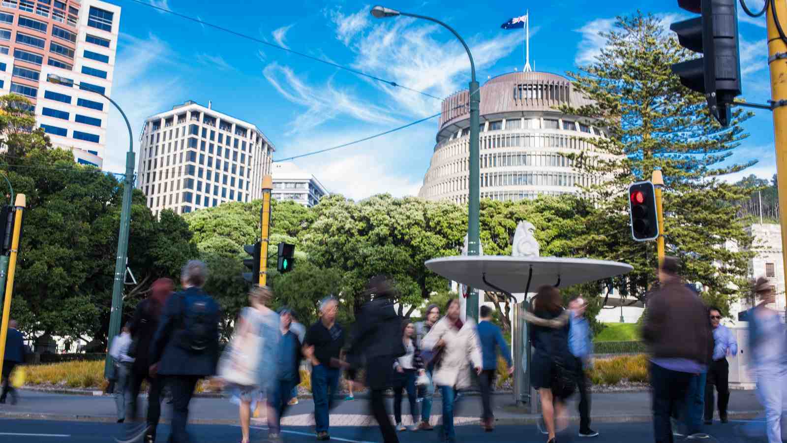 A time-lapse image of commuters walking across a road with parliament’s “Beehive” building in the background.