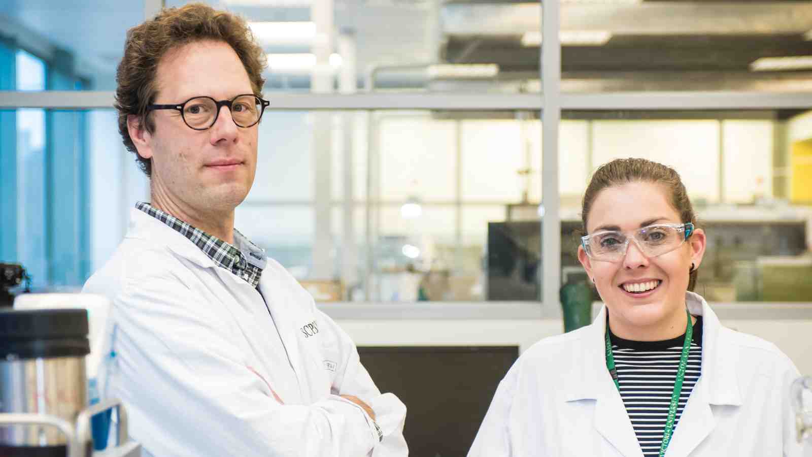Professor Thomas Nann and Dr Renee Goreham stand in their laboratory wearing white coats.