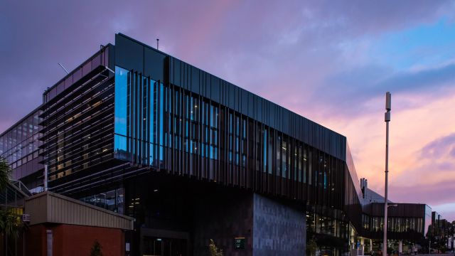 The outside of a windowed building with a pink and purple sky in the background – Te Toki a Rata has won a NZIA annual Local Architecture Award in the Education Category.