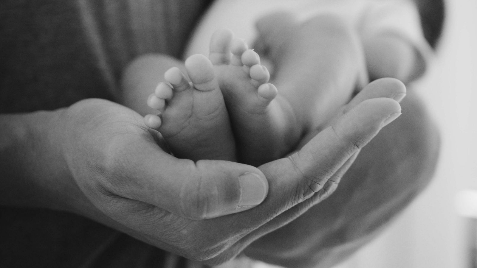 An adult supporting a baby's feet