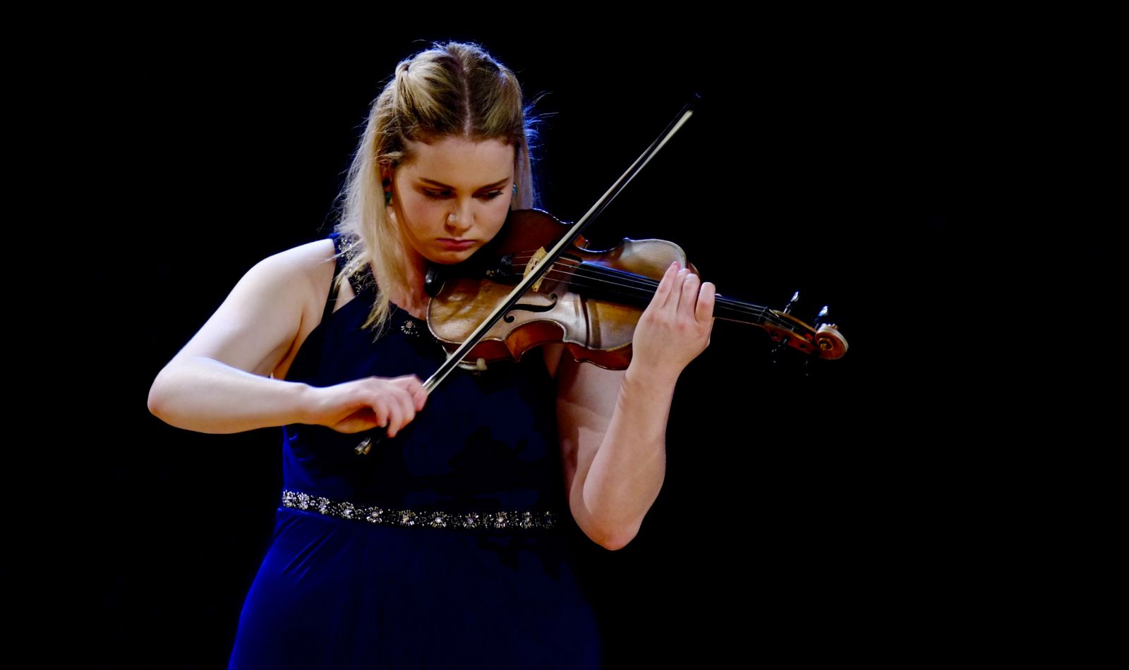 Mid shot of Claudia Tarrant-Matthews playing the violin in a concert setting