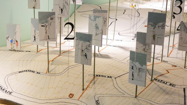 Embroidered map with architectural drawings of streets and houses added to it