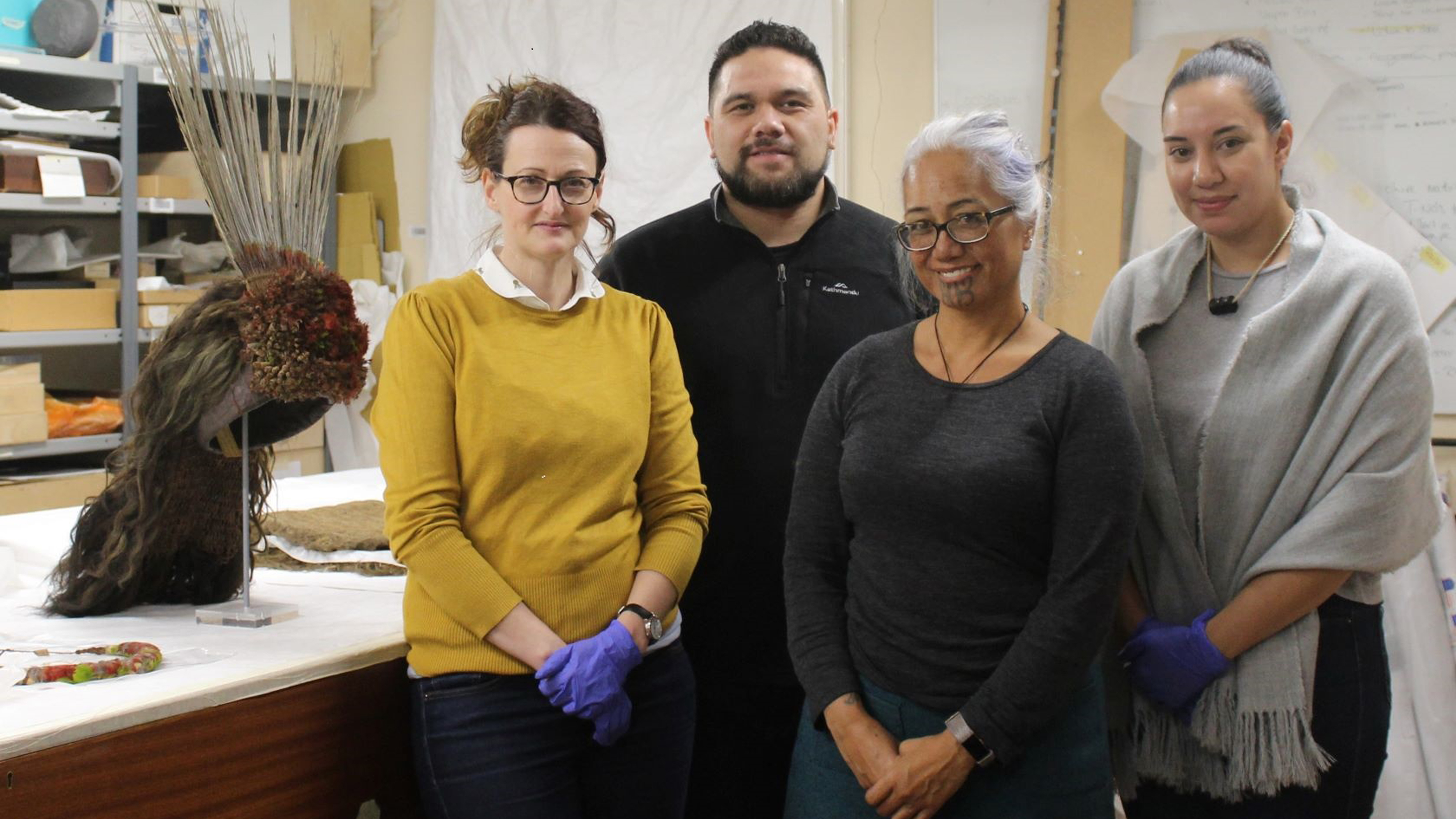 Four people stand next to an art table