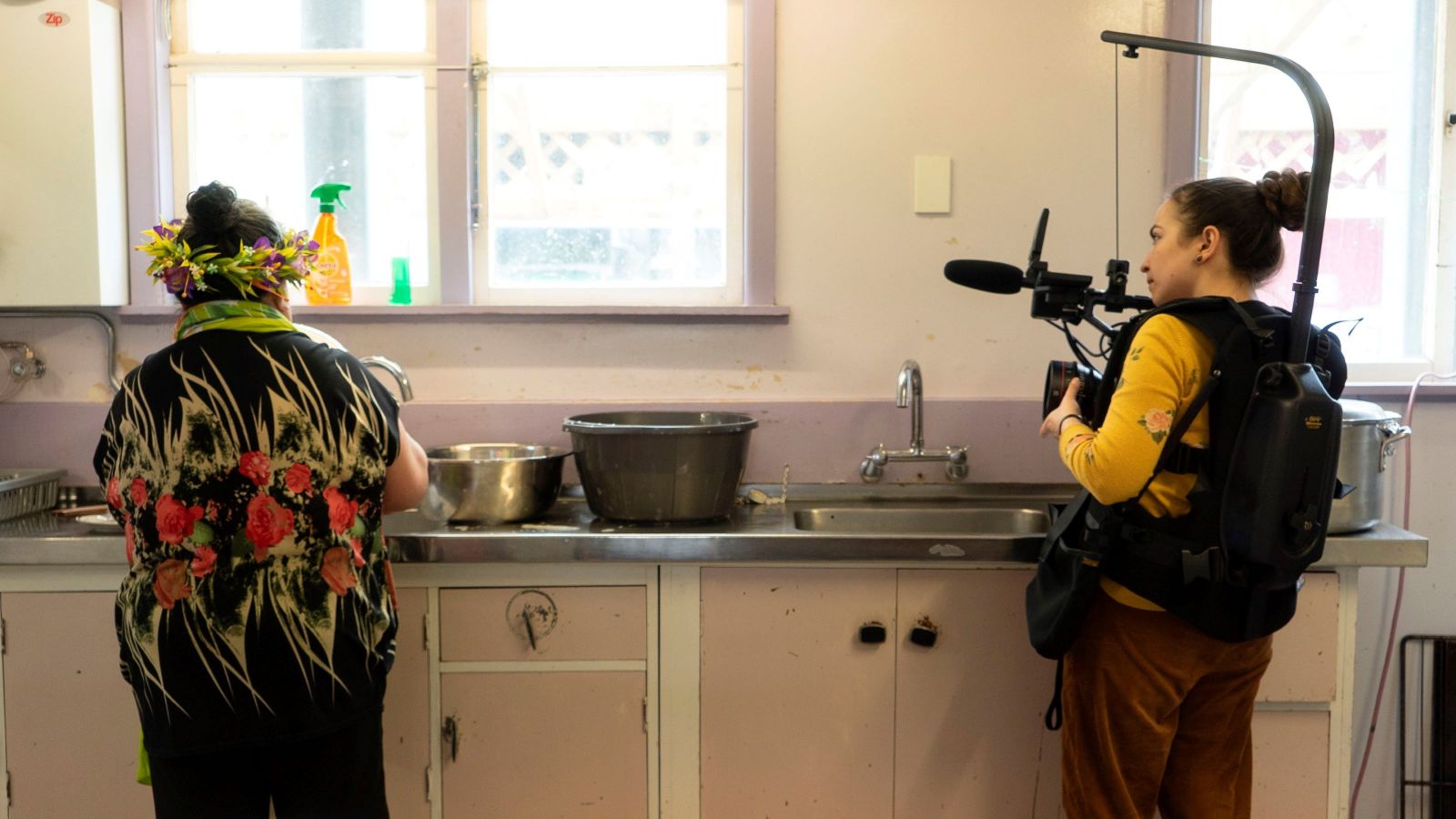 Student films woman in kitchen.