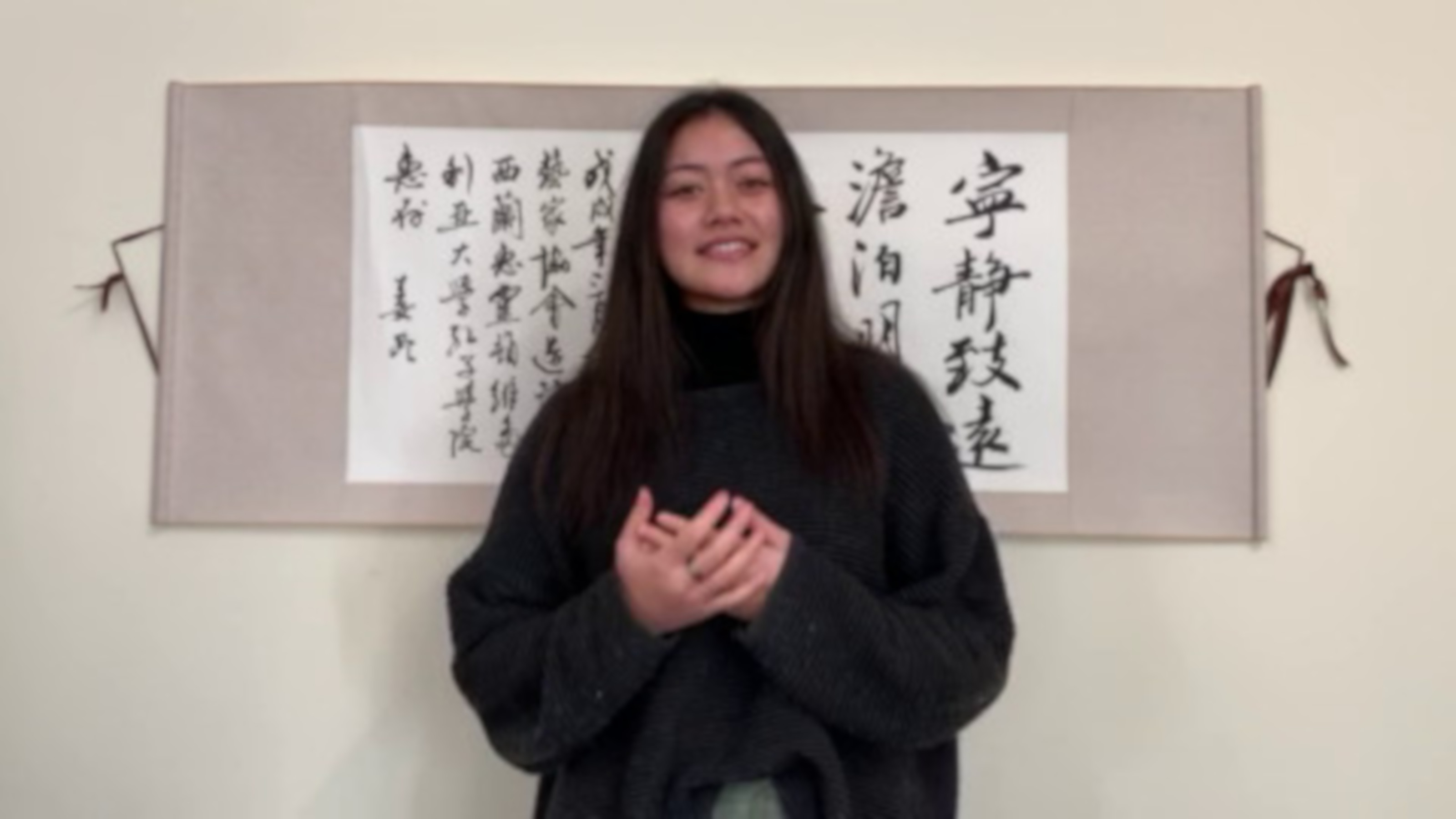 Monica Saili gives her winning speech in front of a piece of Chinese calligraphy