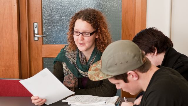 A closeup shot of a person writing with cup in background