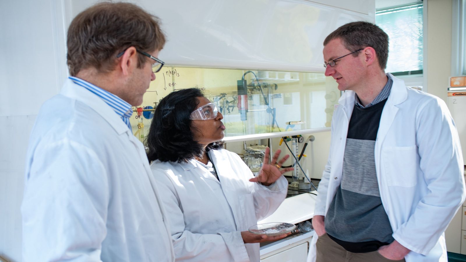 Three scientists having a conversation in a lab