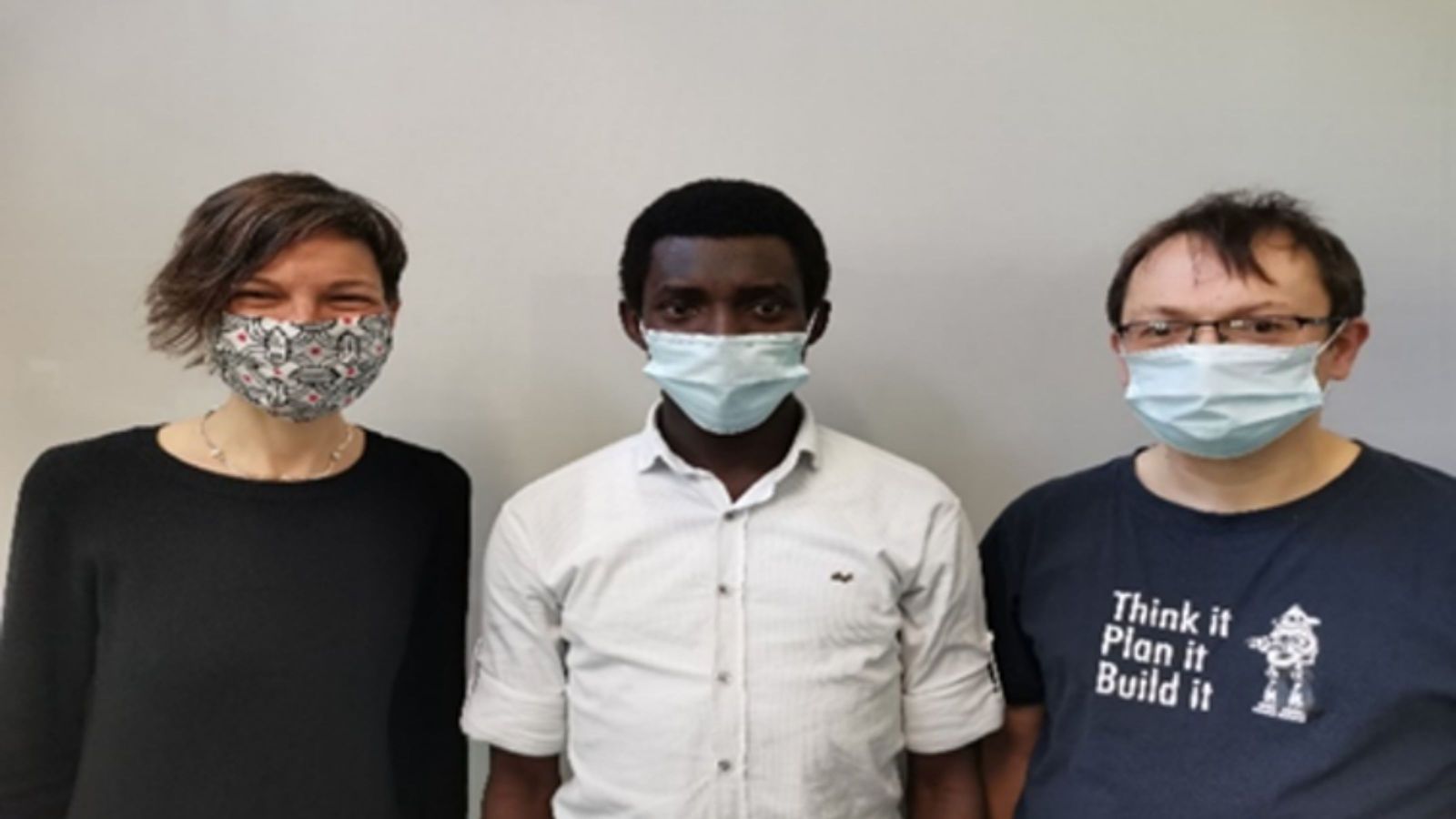 Three people wearing masks, one white female, one dark-skinned male, one white male.