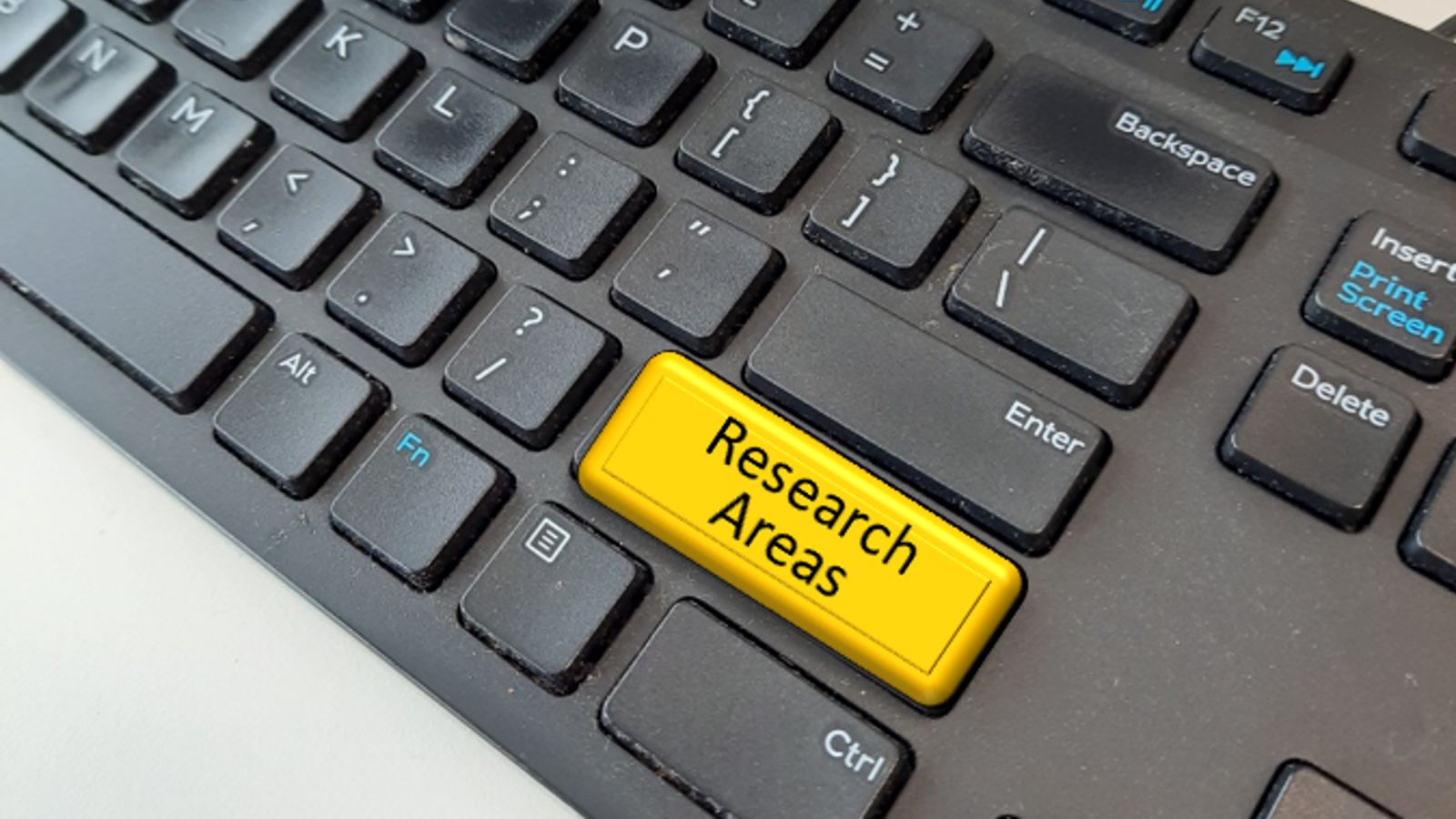 Close up of computer keyboard with fake yellow key saying 'Research areas'