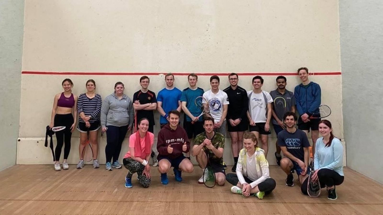 Group picture of players and their gear in squash room.