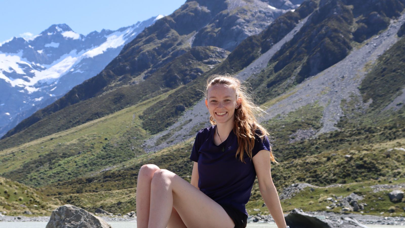 Woman sitting on rock with mountains in the background