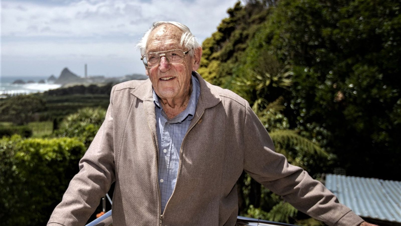 Older man smiling off to the right of camera, New Plymouth waterfront in distance