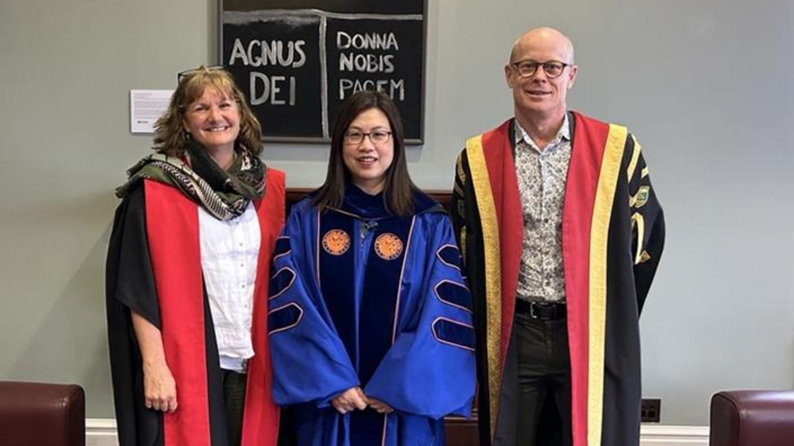 two female and male smiling in academic dress
