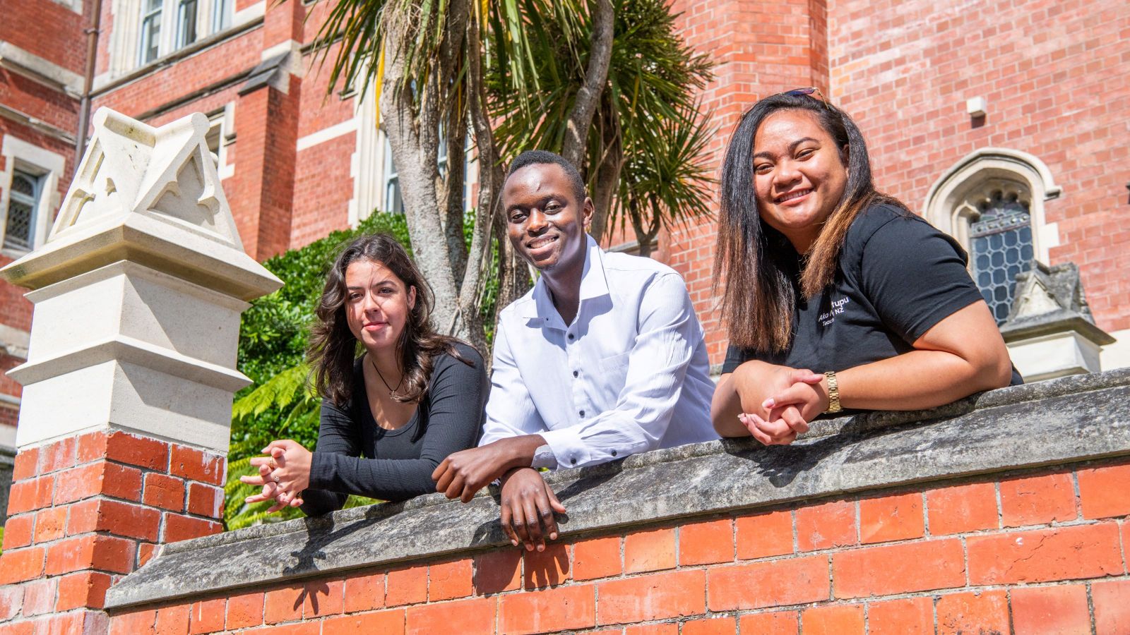 Three scholarship recipients, a boy and two girls are smiling on the Hunter building landing