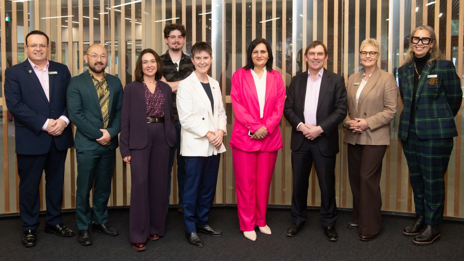 nine people standing in front of wooden slat wall