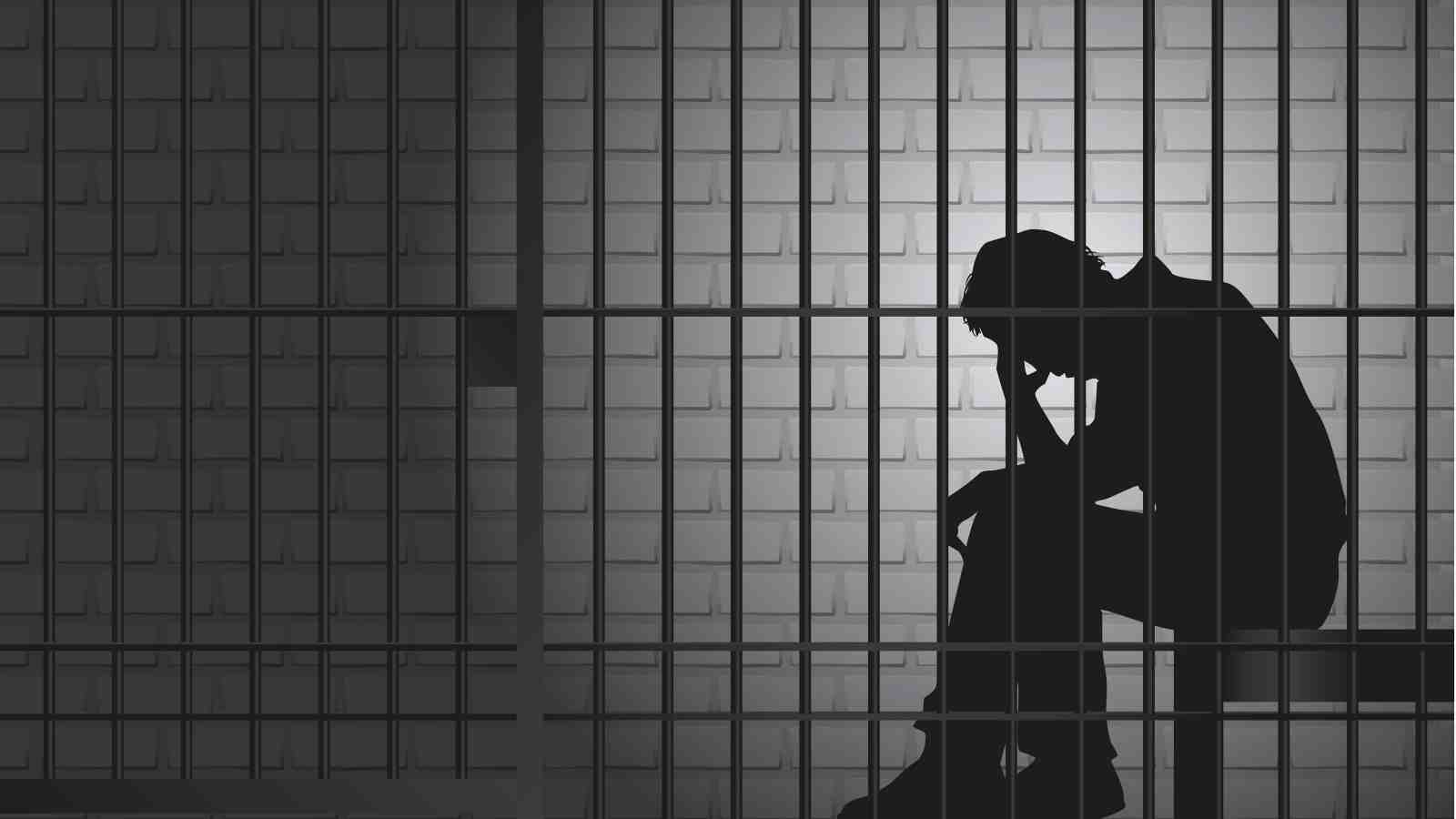 Silhouette of a prisoner behind bars.